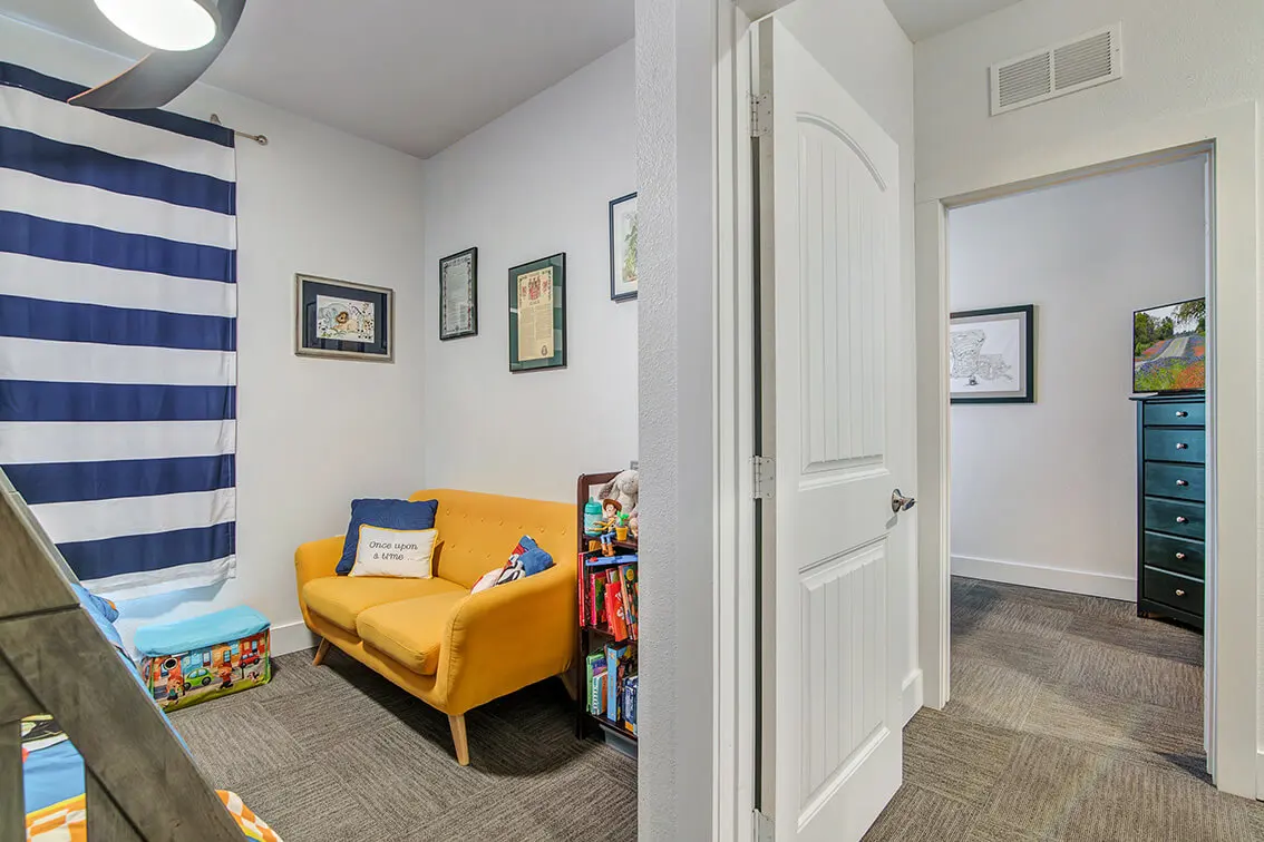 Carpeted room with a small sofa next to an open bedroom door at 404 Industrial Park (7)