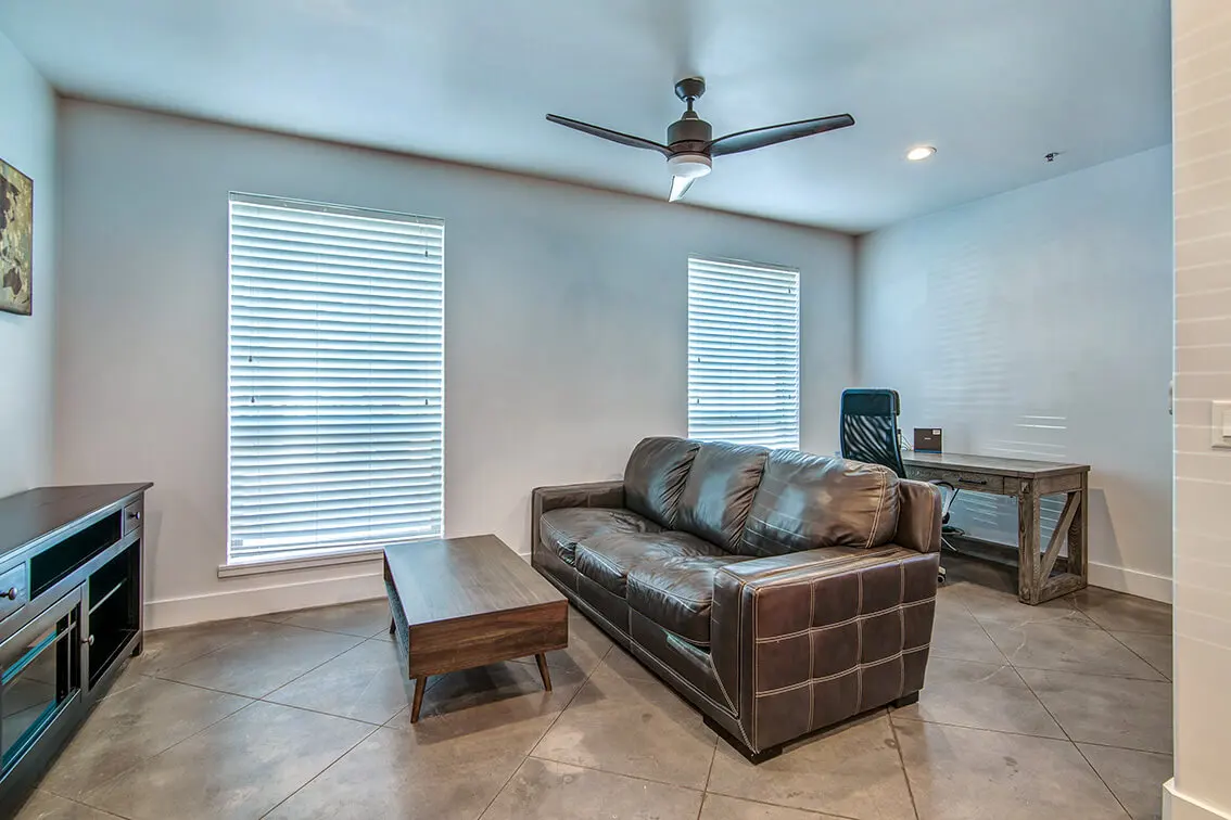 Living room at 404 Industrial Park with stained concrete floors, a ceiling fan and two windows (10)