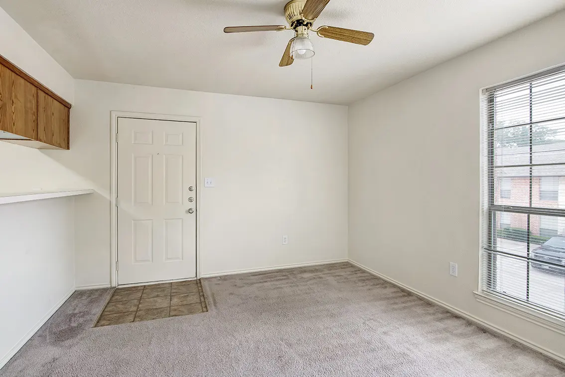 Carpeted Cole Place living room with a ceiling fan, large window and tiled entry by the front door (5)