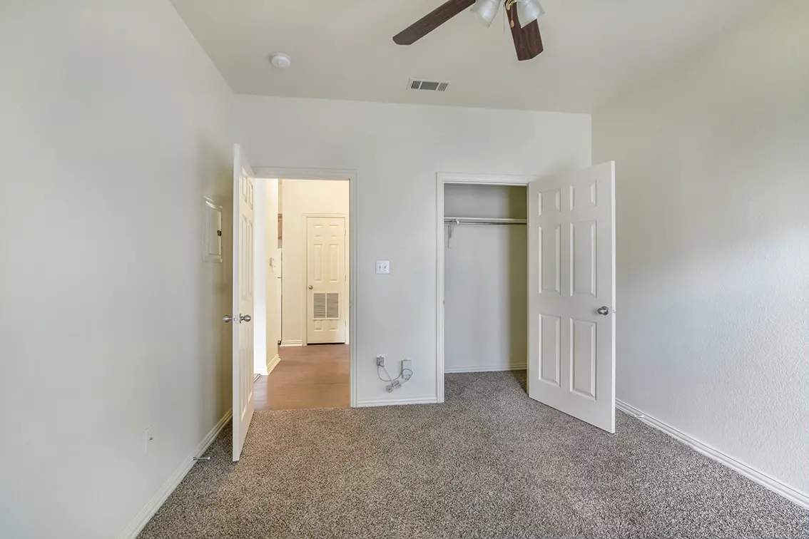 Lone Star bedroom with a ceiling fan, open closet and a door to the hall (12)